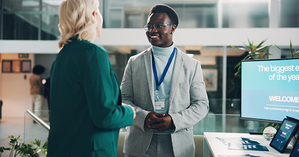 A student and recruiter shaking hands at a professional career fair.